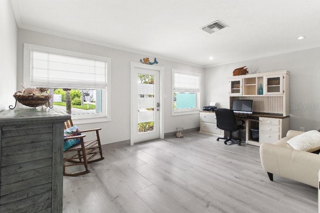 A bright home office features light wood-look flooring, a white desk hutch, and a rocking chair — 810 25TH AVENUE W, PALMETTO, FL