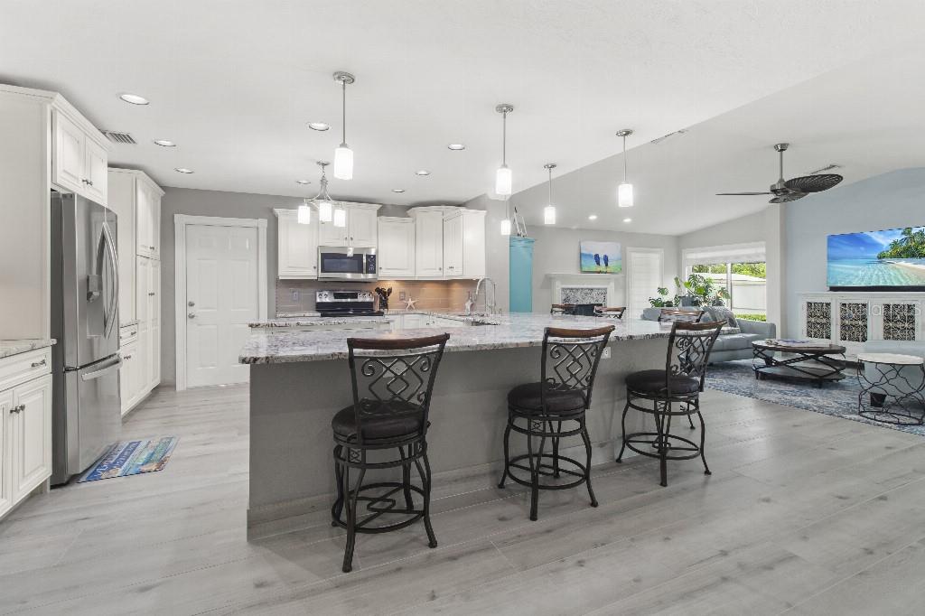 A modern kitchen with white cabinets, granite countertops, and a large island with three stools — 810 25TH AVENUE W, PALMETTO, FL
