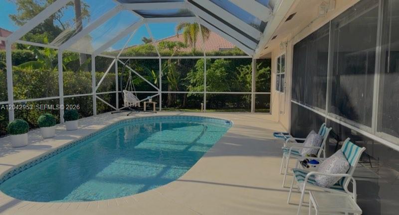 A screened-in patio features a swimming pool, outdoor seating, and lush landscaping in the background — 165 Cypress Trce, Royal Palm Beach FL 33411, ROYAL PALM BEACH, FL