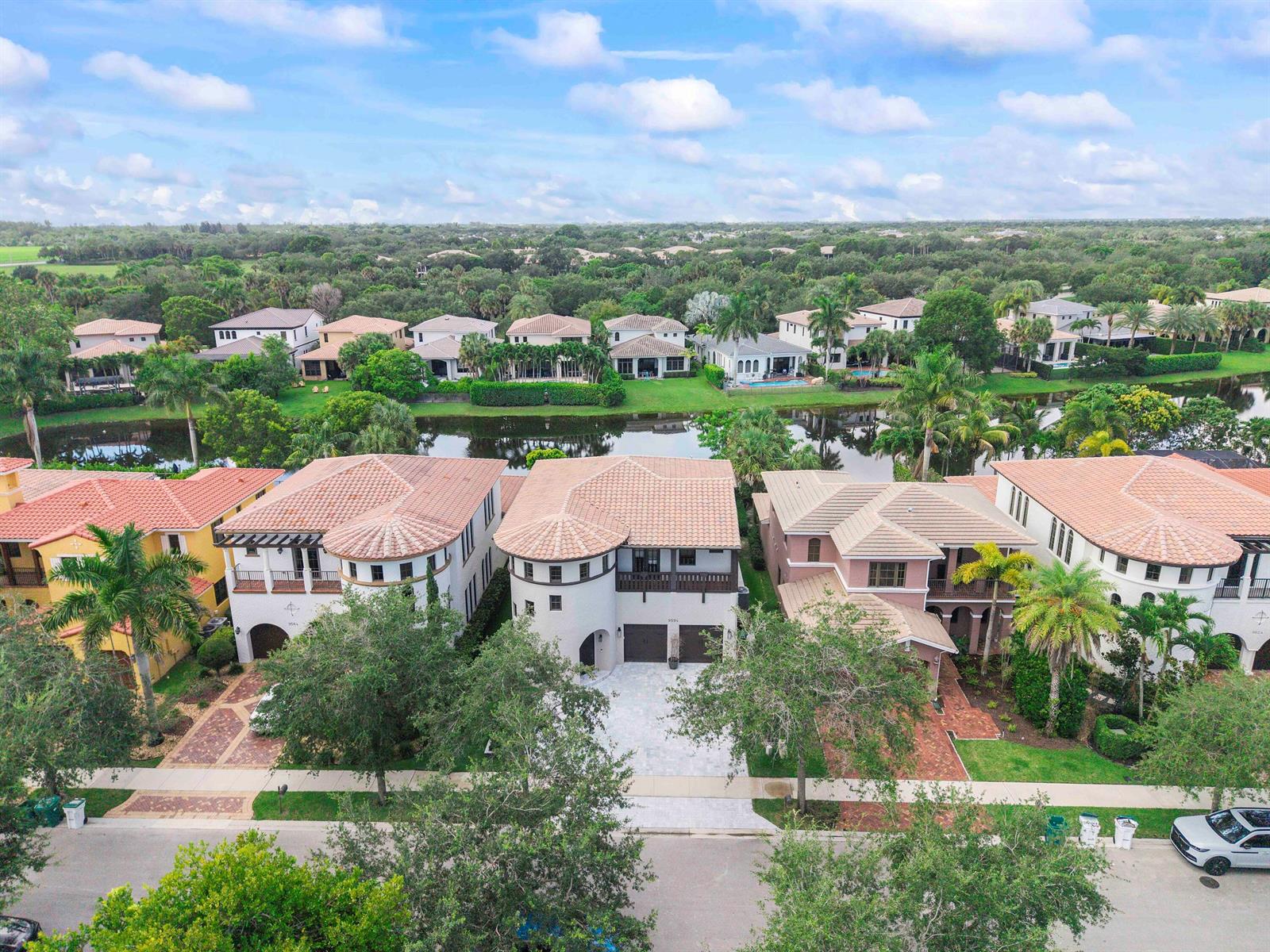 An aerial view shows several large, multi-story houses with tile roofs situated along a canal — 9594 Ginger Court, Parkland FL 33076, PARKLAND, FL