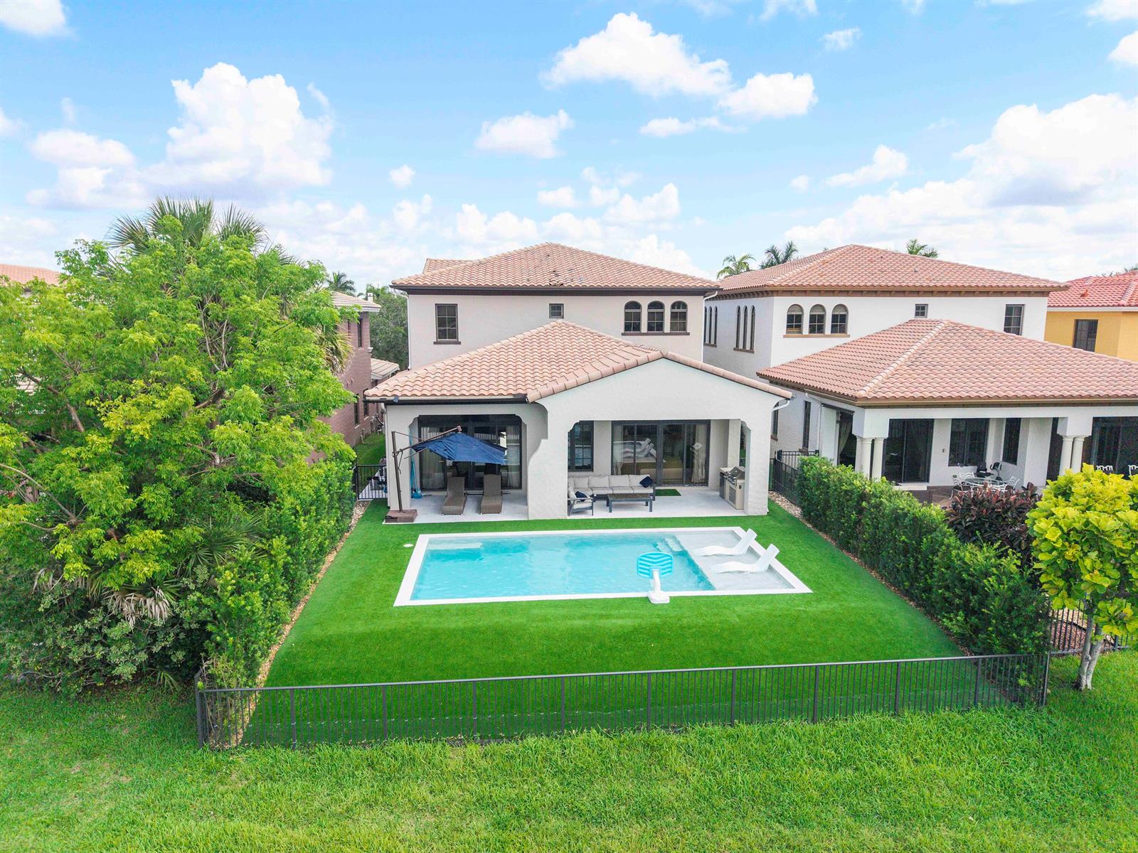 An aerial view of a two-story house with a backyard pool and artificial turf lawn — 9594 Ginger Court, Parkland FL 33076, PARKLAND, FL