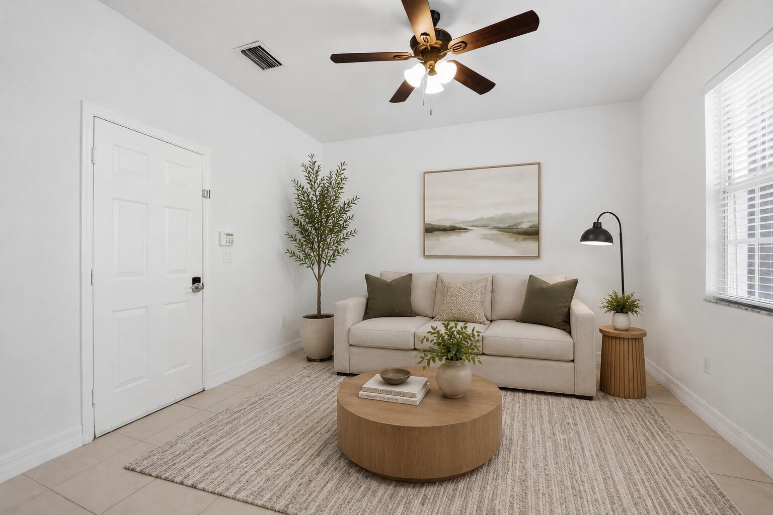 A living room features a beige sofa, round wooden coffee table, and a ceiling fan — 107 Ocean Cay Way, Hypoluxo FL 33462, HYPOLUXO, FL