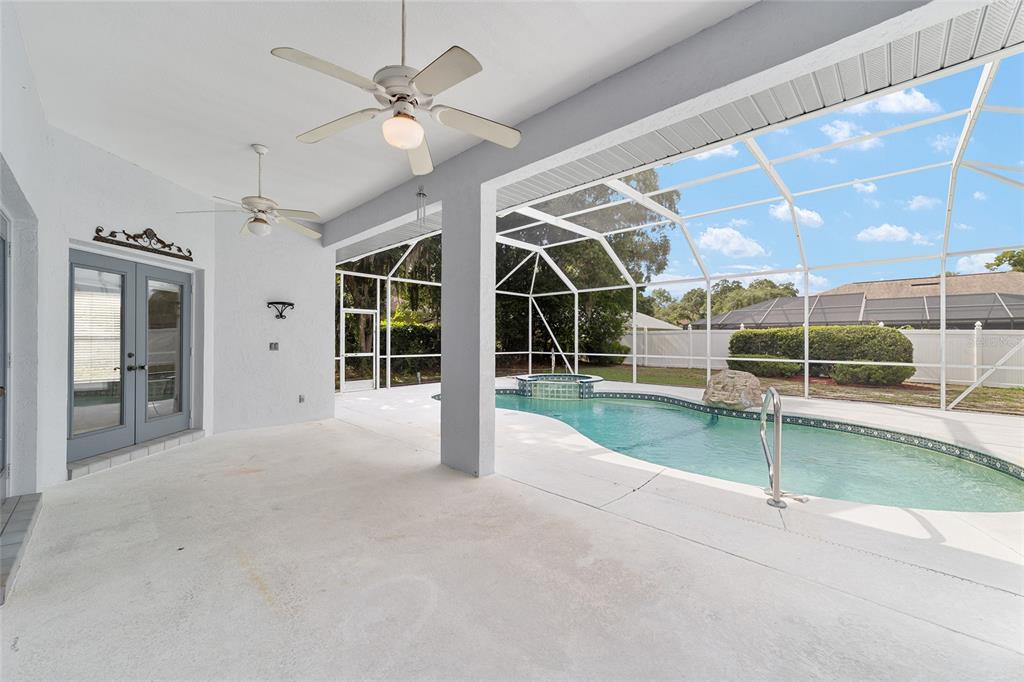A covered patio overlooks a screened-in swimming pool and hot tub in a backyard — 5366 SW 86TH PLACE, OCALA, FL