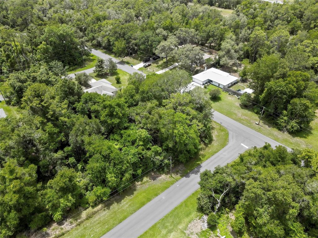 An aerial view shows two houses surrounded by dense trees near a paved road intersection — 1074 W MAXIMILIAN PLACE, CITRUS SPRINGS, FL