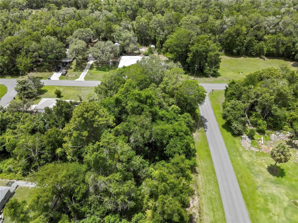 An aerial view shows a wooded lot situated at the corner of two paved roads — 1074 W MAXIMILIAN PLACE, CITRUS SPRINGS, FL