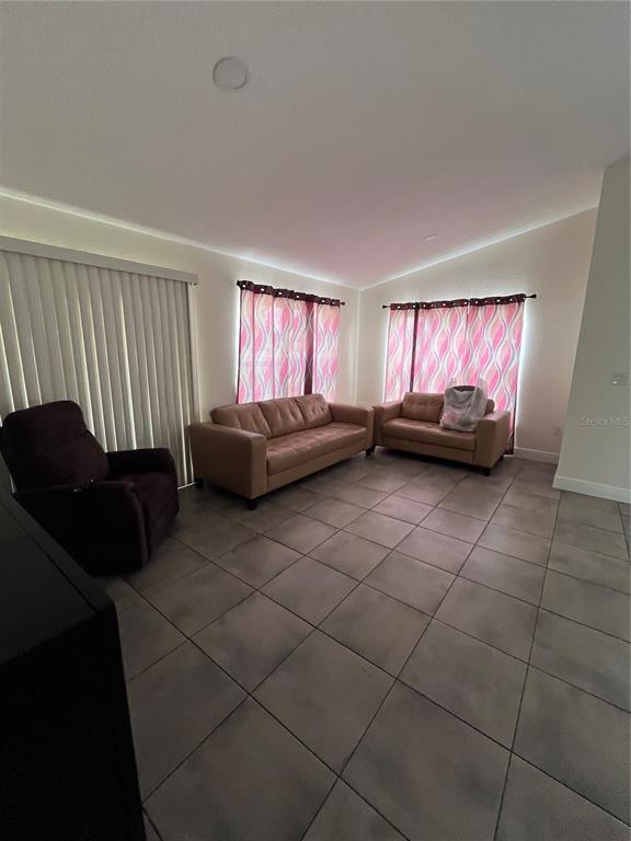 A living room features tan sofas, a dark recliner, pink patterned curtains, and tiled floors — 2127 W PERIO STREET UNIT 1, TAMPA, FL