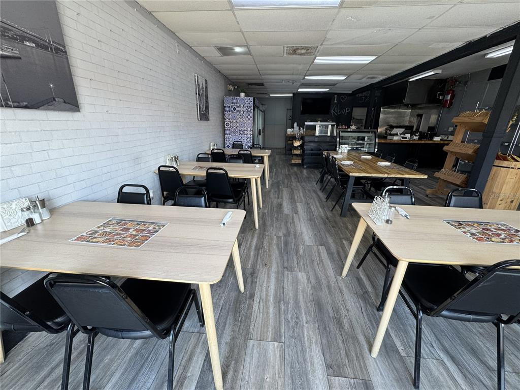A restaurant interior features light wood tables, black chairs, and gray wood-look flooring — 1420 E FLETCHER AVENUE, TAMPA, FL