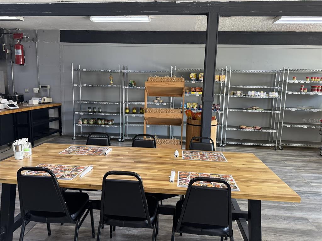 A dining room features a long wooden table with black chairs and metal shelving units — 1420 E FLETCHER AVENUE, TAMPA, FL