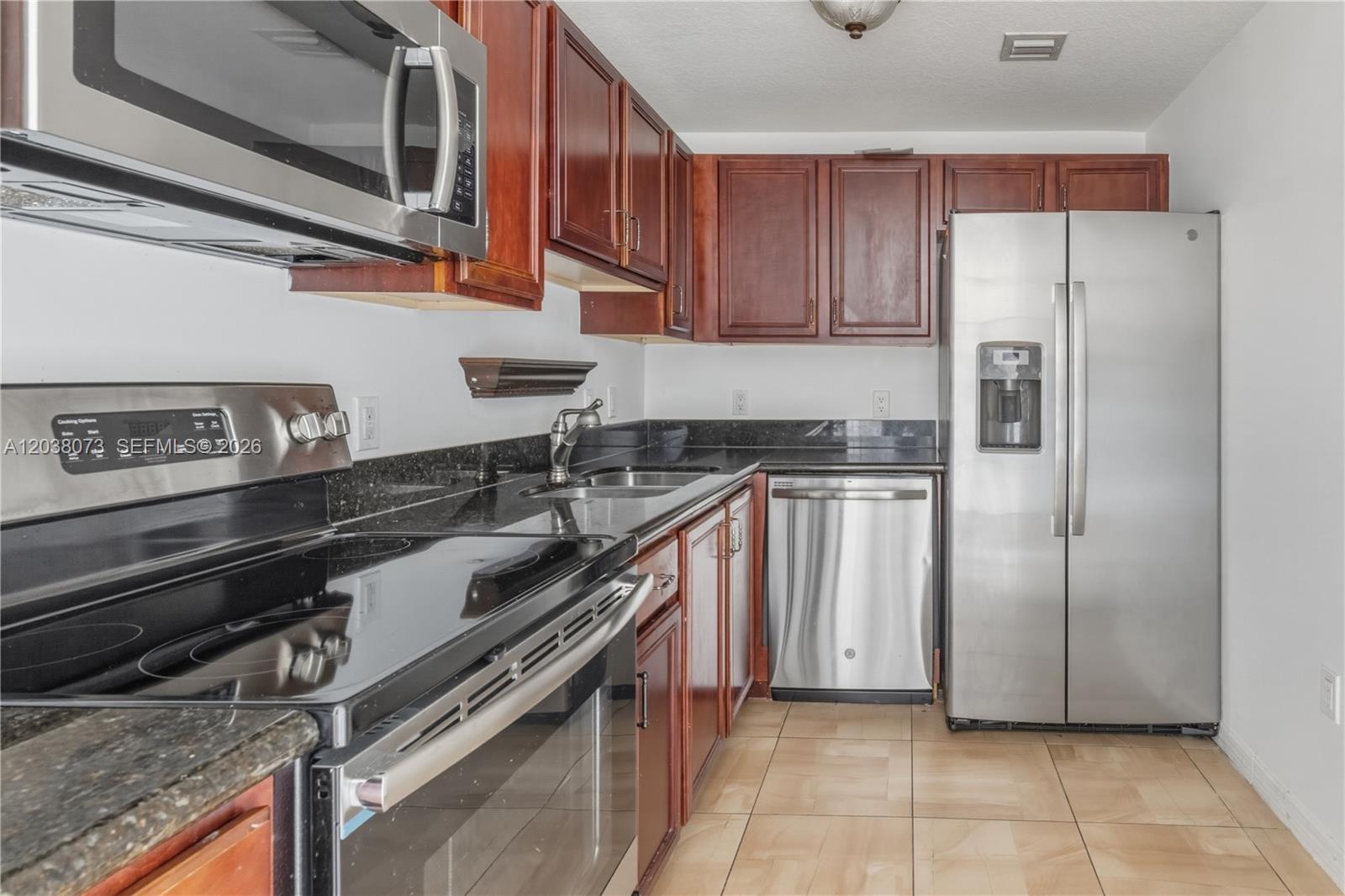 A kitchen features dark wood cabinets, black granite countertops, and stainless steel appliances — 5271 SW 8th St # 304, Miami FL 33134, MIAMI, FL