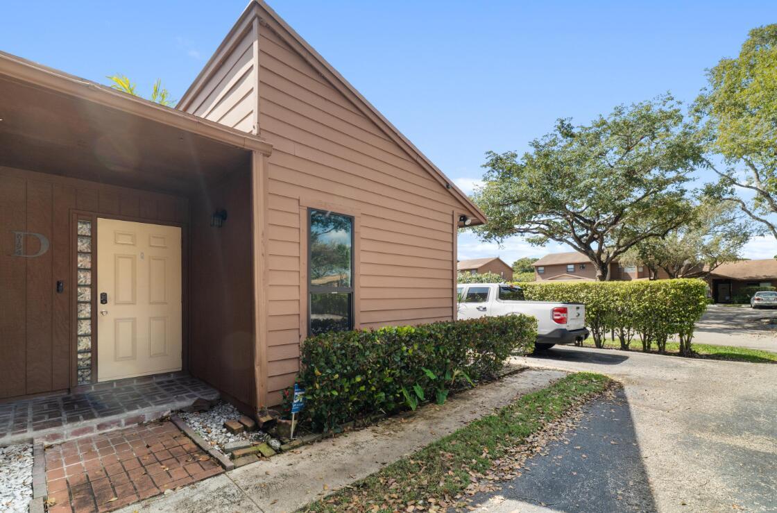 A brown, single-story residential building features a tan front door and a brick walkway — 6194 Pine Tree Lane # D, Tamarac FL 33319, TAMARAC, FL