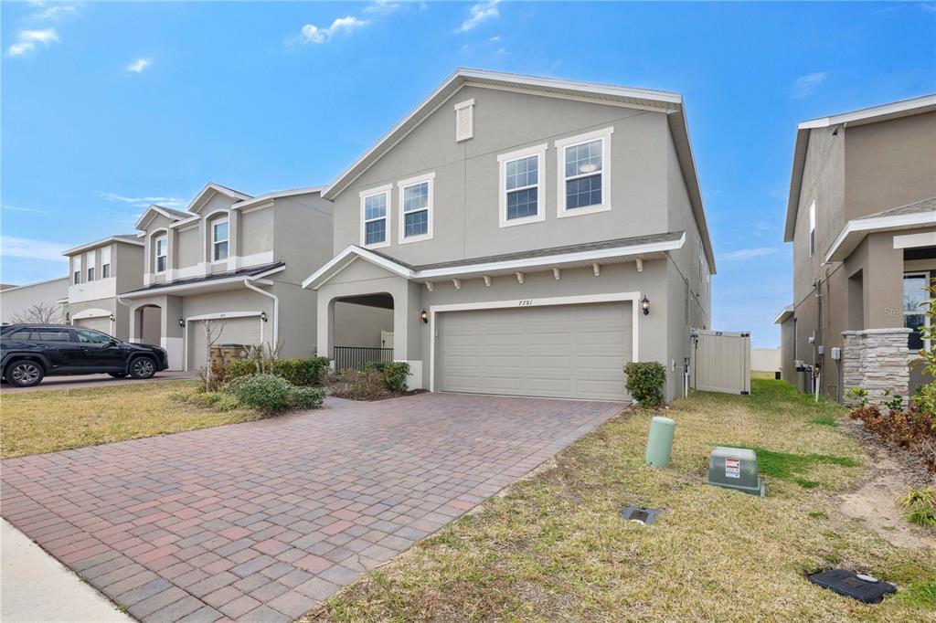 A two-story suburban house with a gray exterior, a paved driveway, and a two-car garage — 7781 MARSALA STREET, CLERMONT, FL