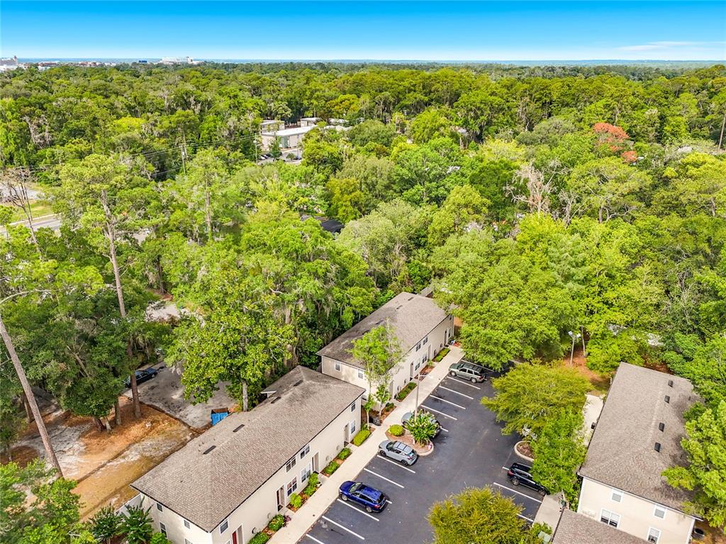 An aerial view shows two multi-story apartment buildings with parking lots surrounded by dense trees — 1710 NW 7TH STREET UNIT 604, GAINESVILLE, FL