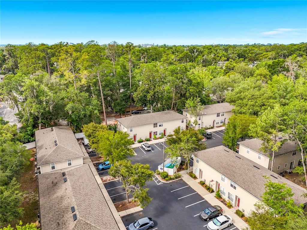 An aerial view shows several multi-unit residential buildings surrounded by trees and parking lots — 1710 NW 7TH STREET UNIT 604, GAINESVILLE, FL