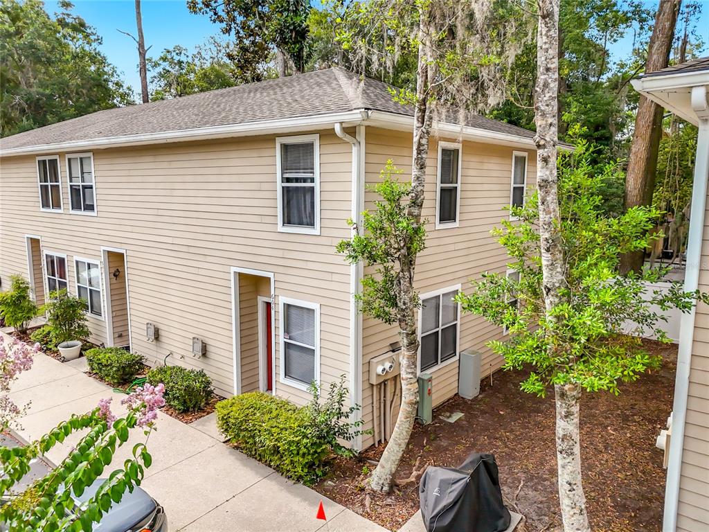 An exterior view of a two-story tan siding townhouse with a concrete walkway and landscaping — 1710 NW 7TH STREET UNIT 604, GAINESVILLE, FL