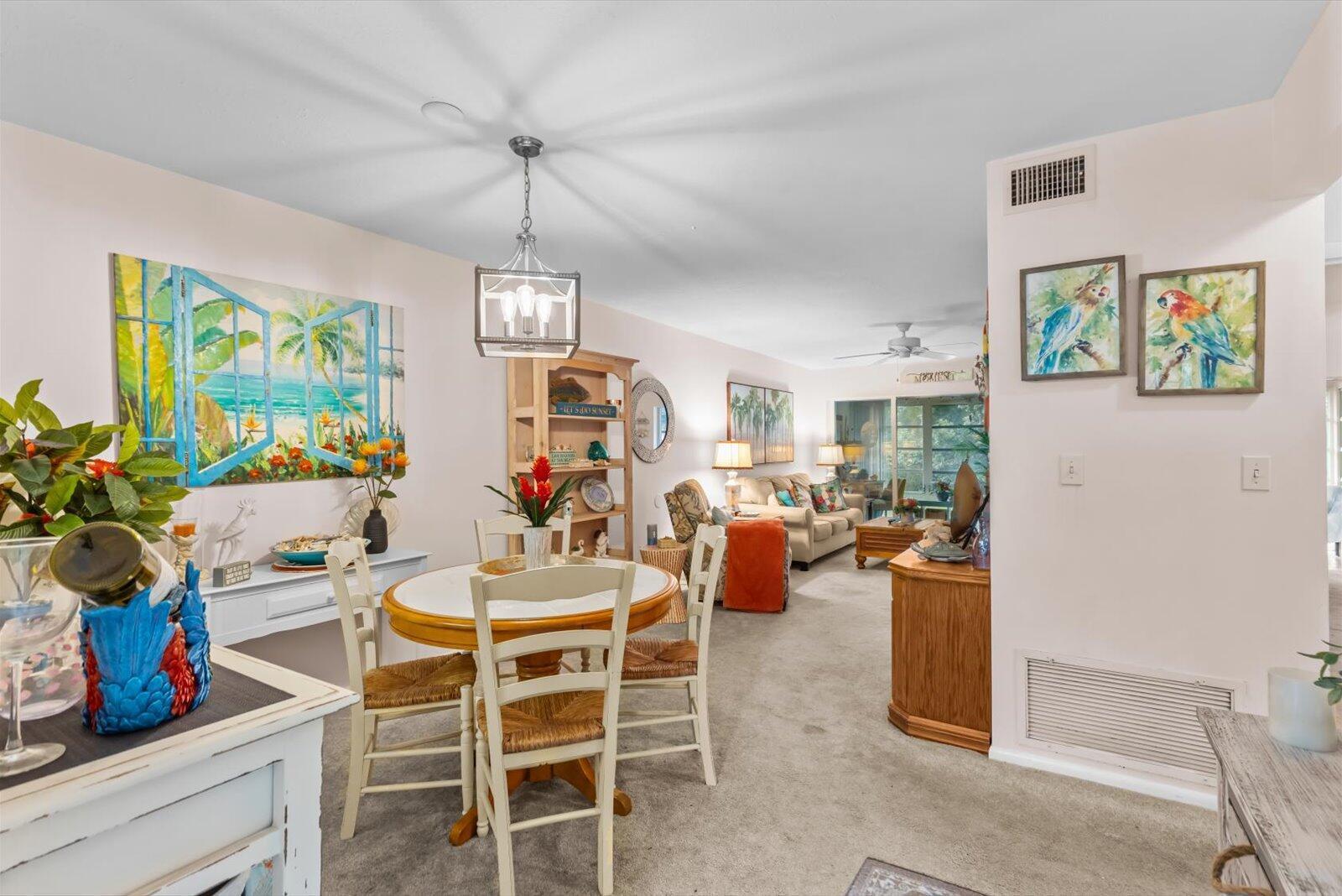 A dining area with a round table and chairs opens into a carpeted living room — 2929 SE Ocean Boulevard # 130, Stuart FL 34996, STUART, FL