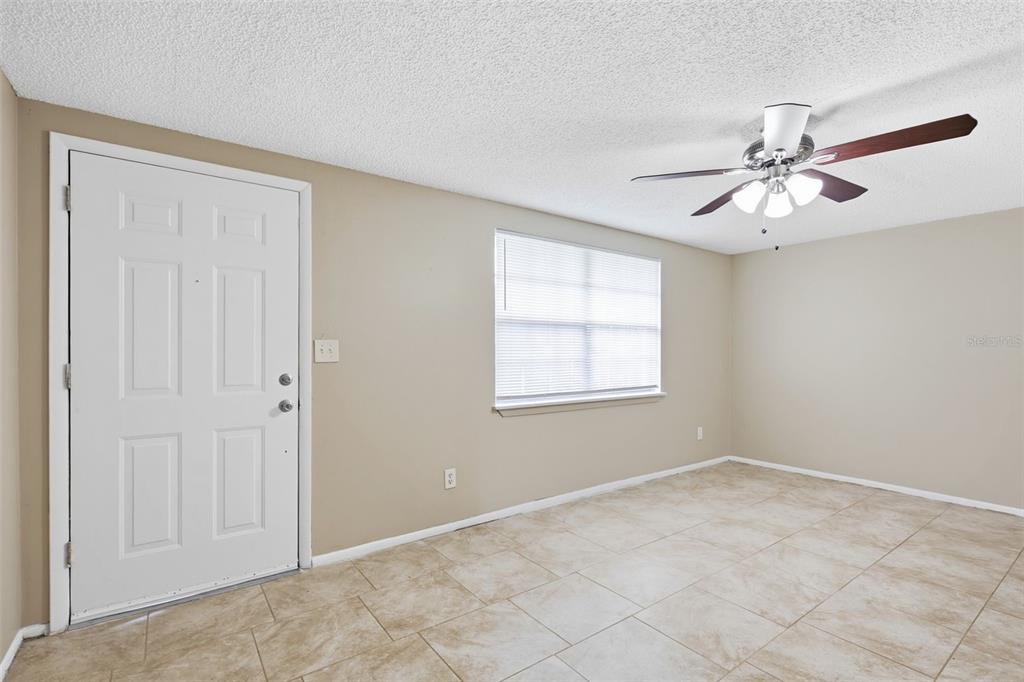 A room with beige walls, tile flooring, a white front door, and a ceiling fan — 3453 WILSON DRIVE, HOLIDAY, FL