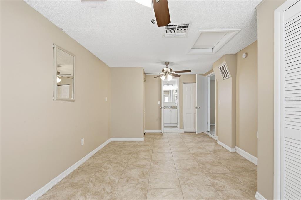 An empty room with beige walls, tile flooring, a ceiling fan, and a doorway — 3453 WILSON DRIVE, HOLIDAY, FL