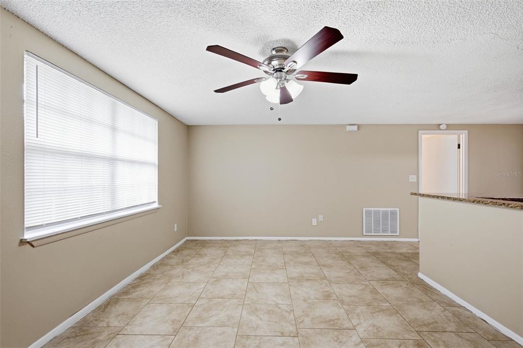 A dining area features tan walls, tile flooring, a ceiling fan, and a large window — 3453 WILSON DRIVE, HOLIDAY, FL