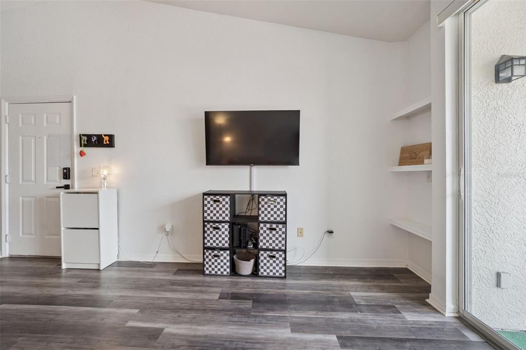 A living room features a wall-mounted television, a cube storage unit, and white shelving — 2513 MAITLAND CROSSING WAY UNIT 304, ORLANDO, FL