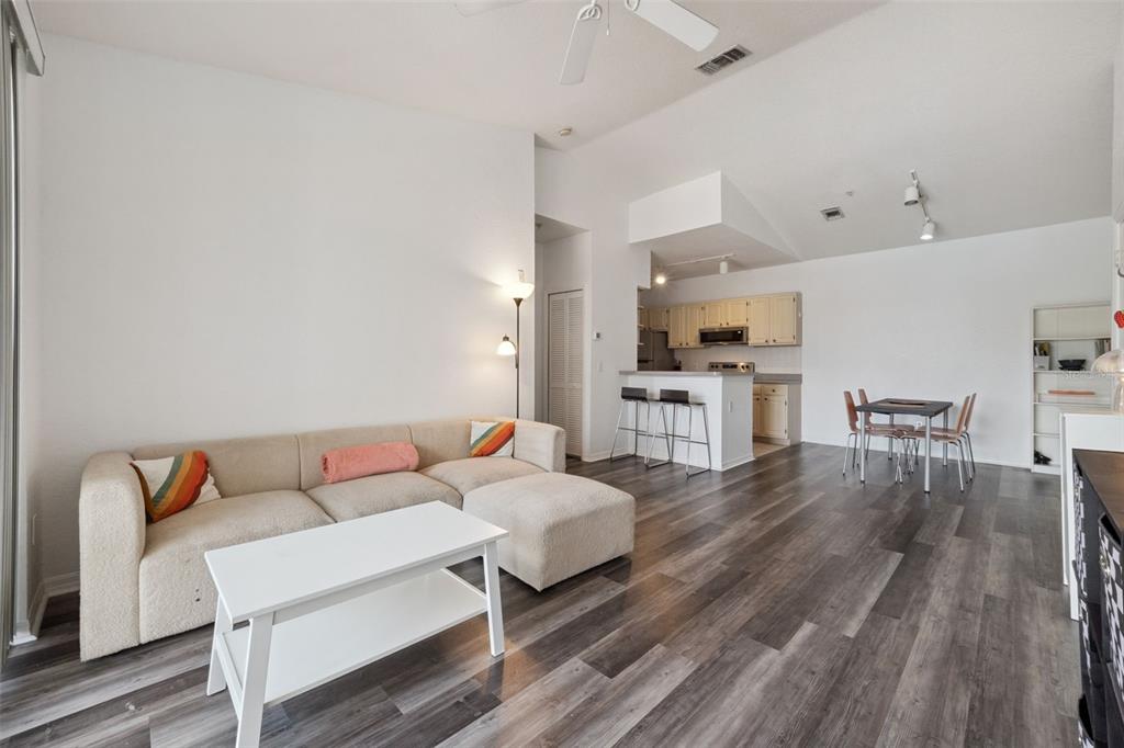 An open-concept living and dining area features light walls, wood-look flooring, and a kitchen island — 2513 MAITLAND CROSSING WAY UNIT 304, ORLANDO, FL
