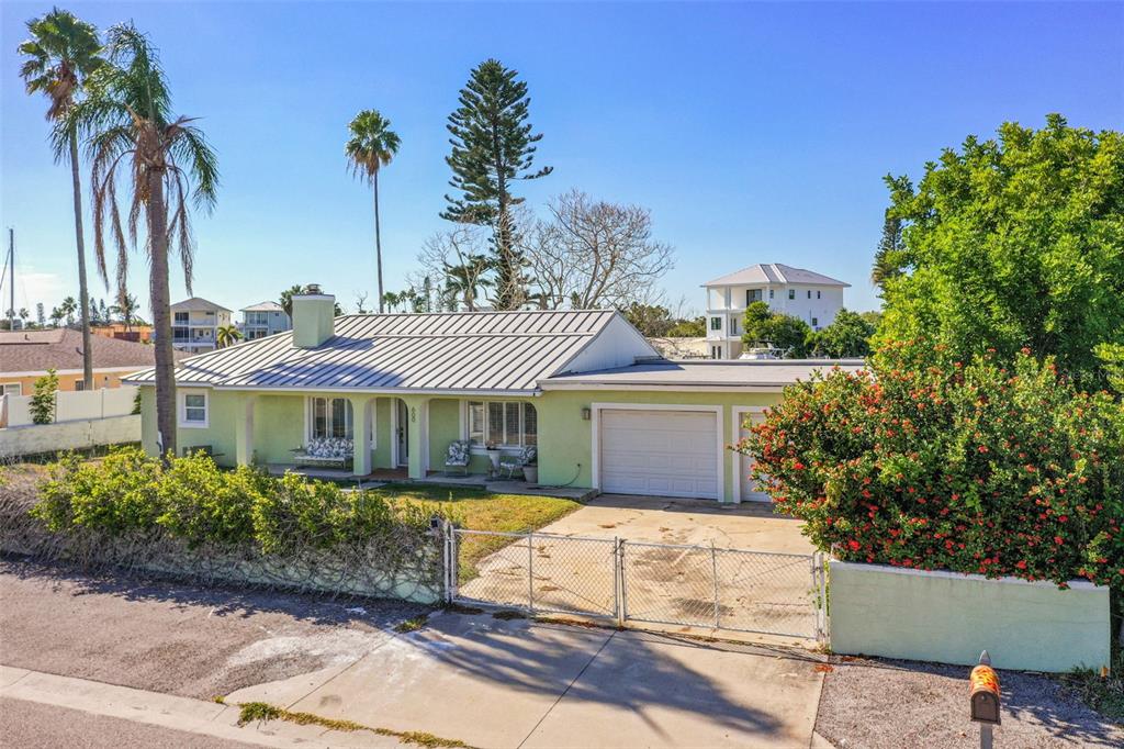 A light green single-story house with a metal roof and a gated concrete driveway — 600 NORMANDY ROAD, MADEIRA BEACH, FL