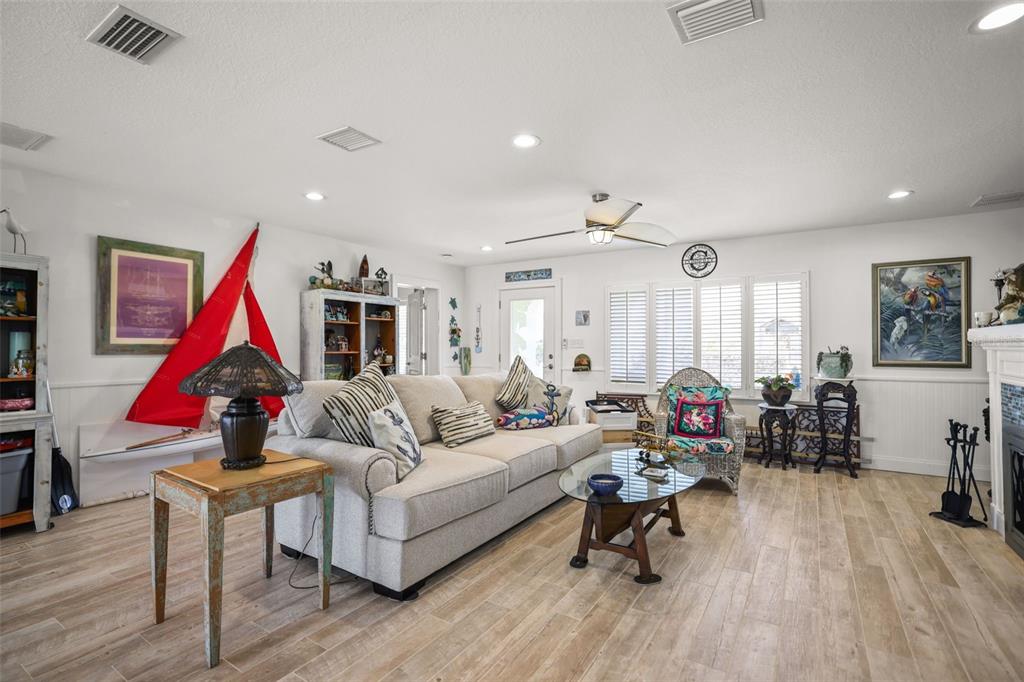 A living room features a beige sofa, a glass coffee table, and light wood-look flooring — 600 NORMANDY ROAD, MADEIRA BEACH, FL