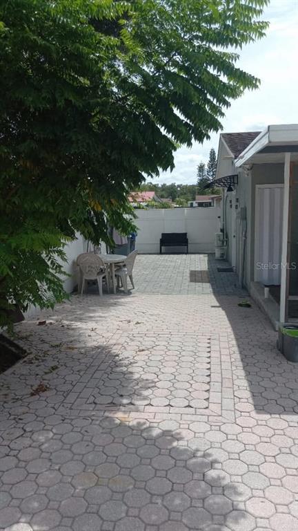 A paved patio area features a small table with chairs beneath a large tree — 7030 24TH AVENUE S, TAMPA, FL