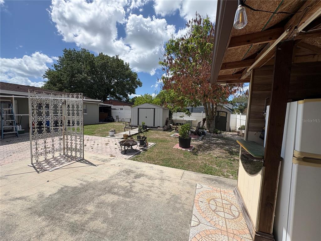 A backyard features a concrete patio, a decorative metal screen, a shed, and landscaping — 7030 24TH AVENUE S, TAMPA, FL