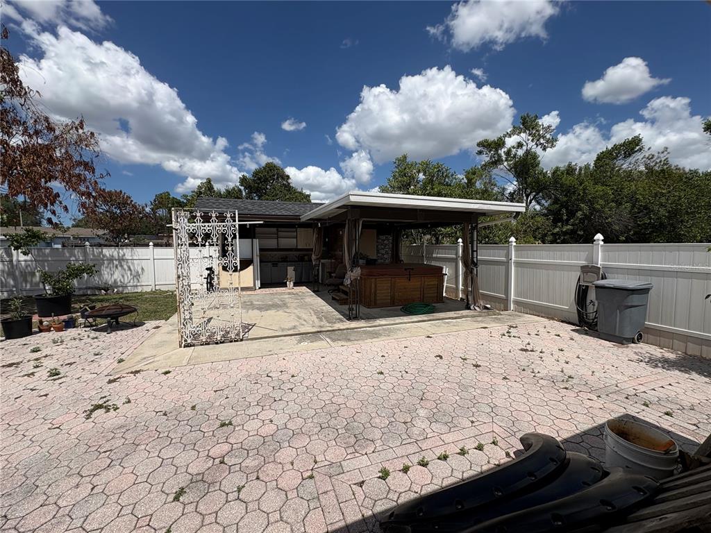 A backyard patio features a covered hot tub area, paved flooring, and a white fence — 7030 24TH AVENUE S, TAMPA, FL