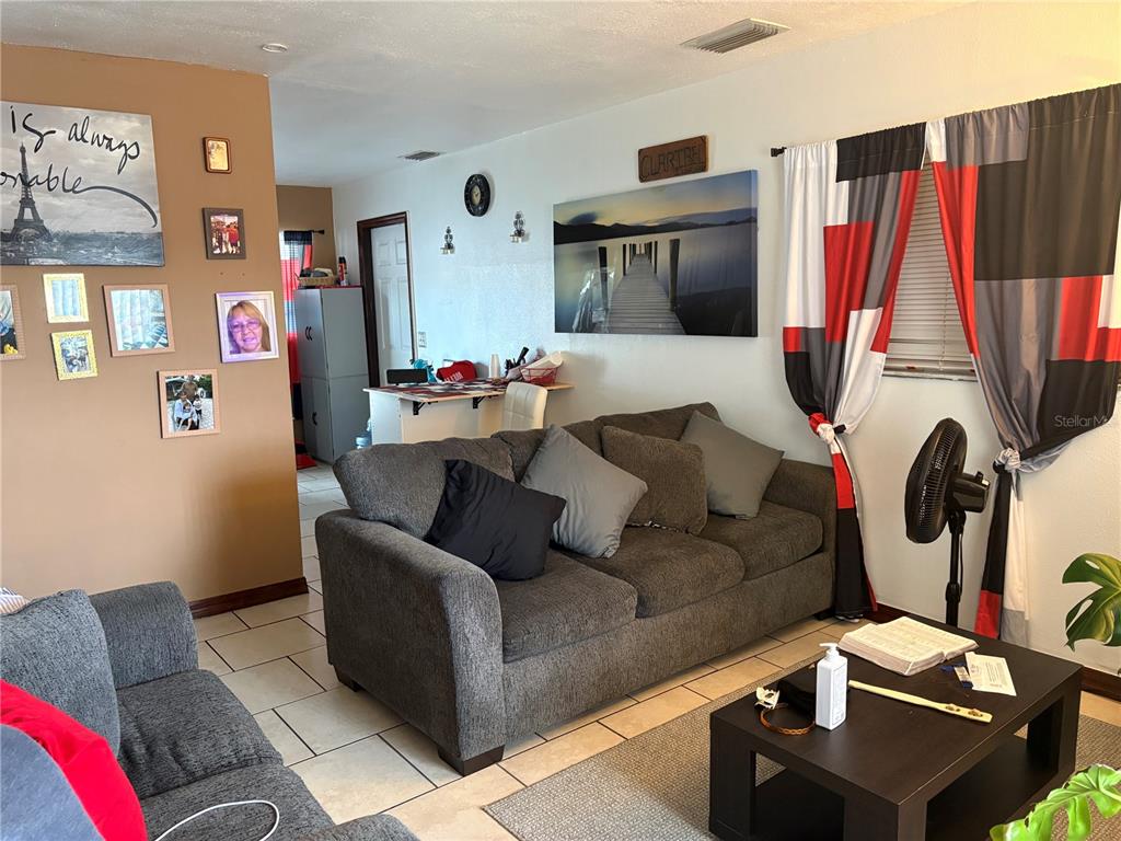 A living room features a grey sofa, a coffee table, and a wall with photos — 7030 24TH AVENUE S, TAMPA, FL