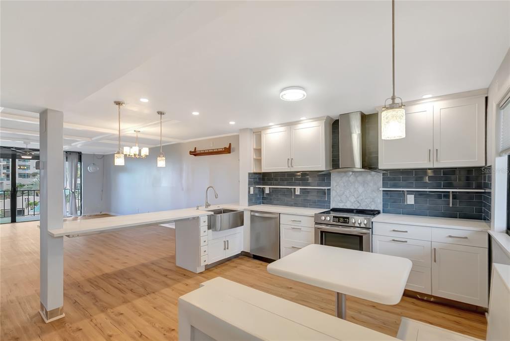 A kitchen features white cabinets, a stainless steel farmhouse sink, and a breakfast bar island — 1581 GULF BOULEVARD UNIT 302N, CLEARWATER BEACH, FL