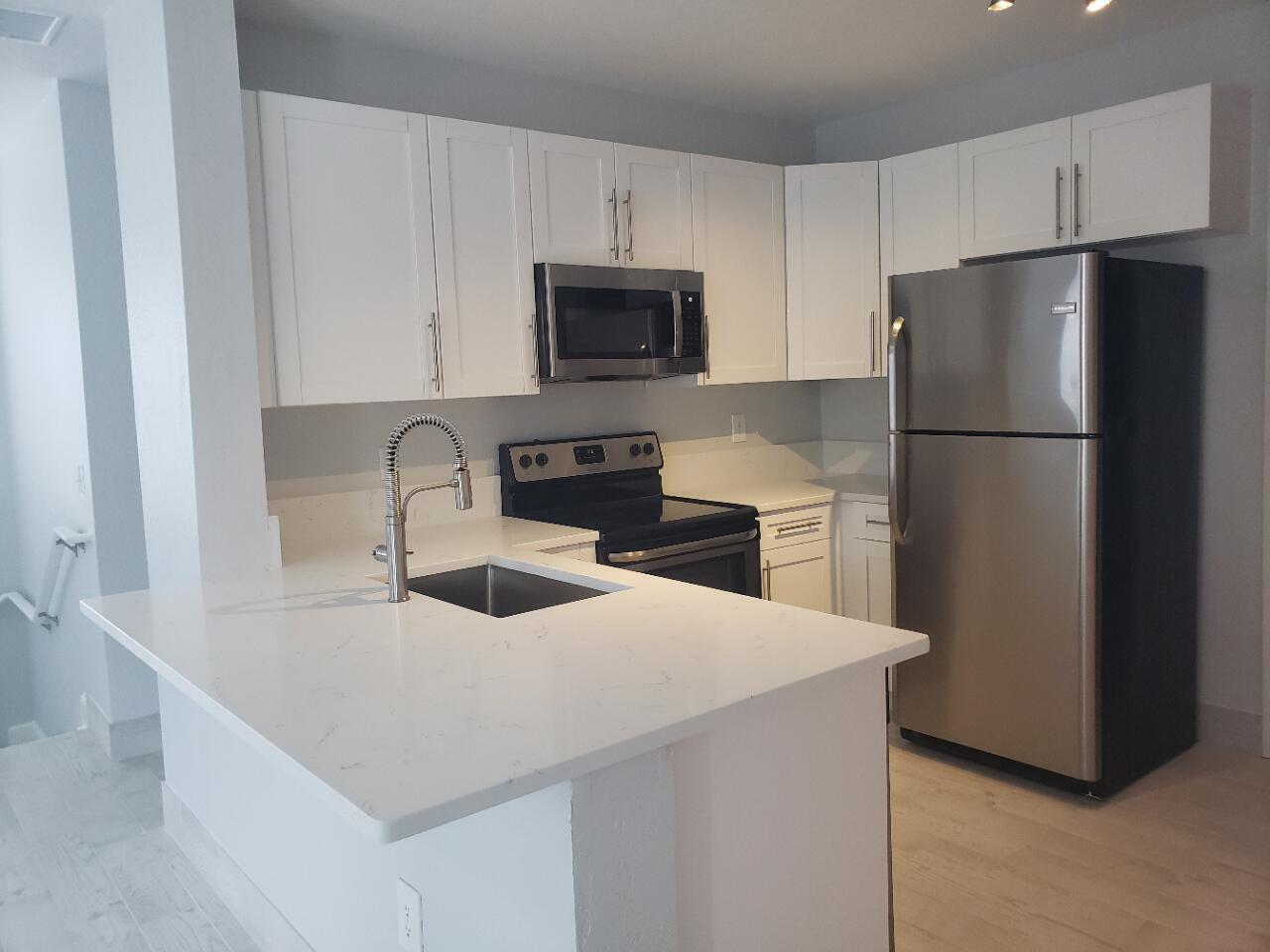 A kitchen features white cabinets, stainless steel appliances, and a white quartz countertop island — 1005 Belmont Place # 1005, Boynton Beach FL 33436, BOYNTON BEACH, FL