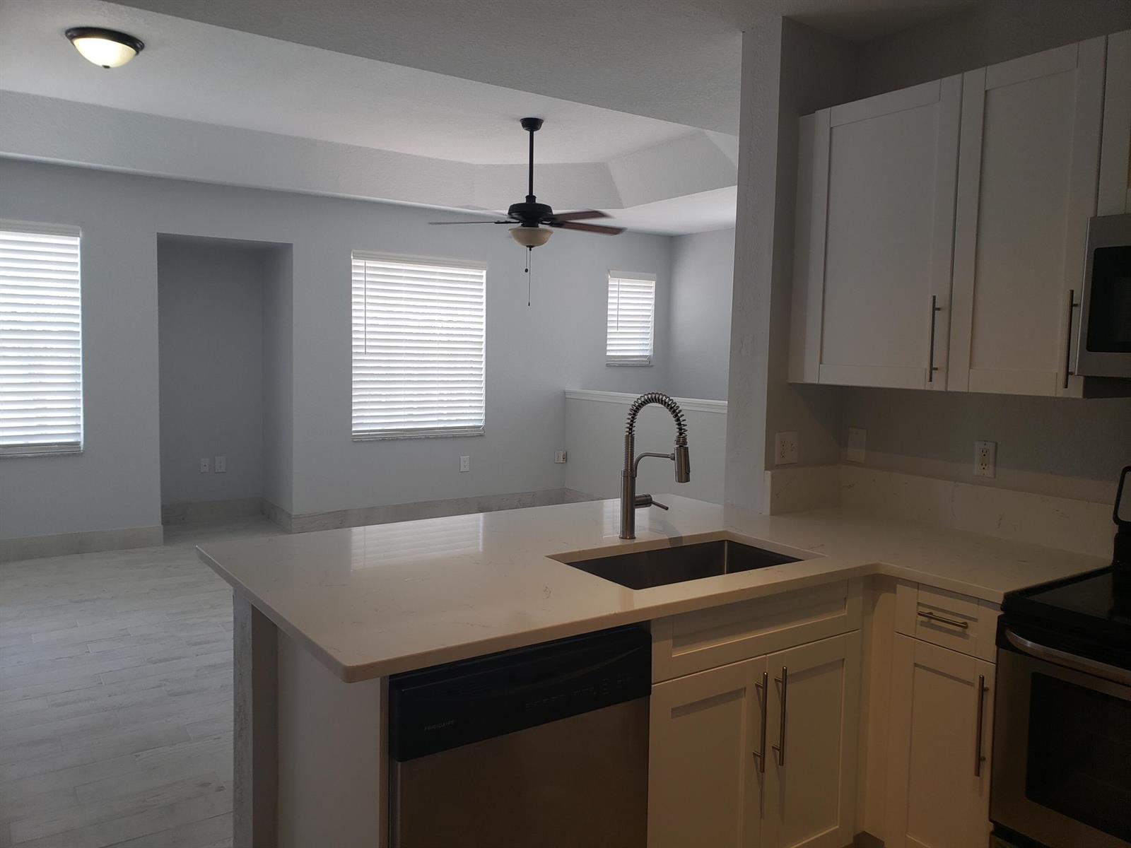 A kitchen with white cabinets and quartz countertops overlooks an open living area — 1005 Belmont Place # 1005, Boynton Beach FL 33436, BOYNTON BEACH, FL