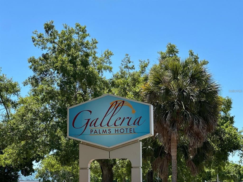 A blue sign for the Galleria Palms Hotel stands outdoors against a background of trees — 3000 MAINGATE LANE UNIT 326, KISSIMMEE, FL