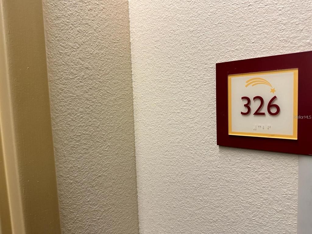 A room number sign labeled 326 is mounted on a textured beige wall — 3000 MAINGATE LANE UNIT 326, KISSIMMEE, FL