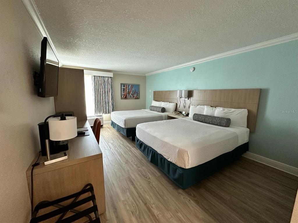 A hotel room features two beds, a desk, a television, and light blue walls — 3000 MAINGATE LANE UNIT 326, KISSIMMEE, FL