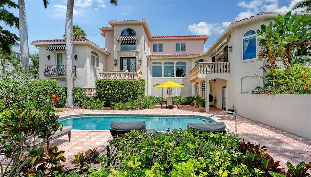 A large two-story house with a swimming pool, patio, and yellow umbrella in the backyard — 1023 TOCOBAGA LANE, SARASOTA, FL