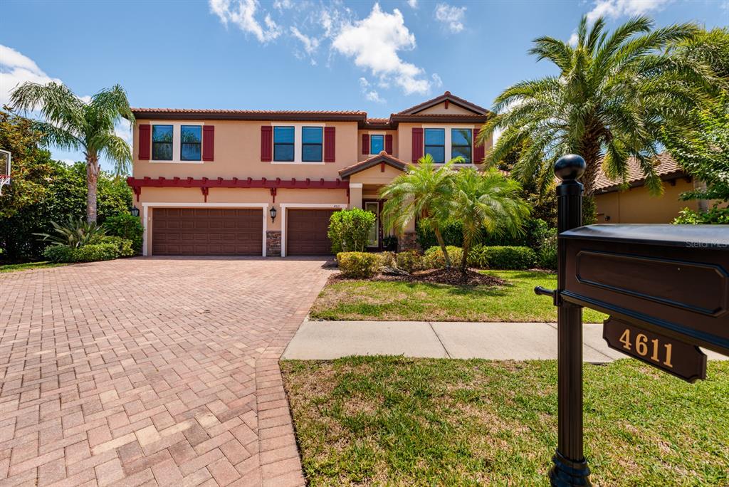 A two-story house with a brick paver driveway and a mailbox in the foreground — 4611 GRAND PRESERVE PLACE, PALM HARBOR, FL