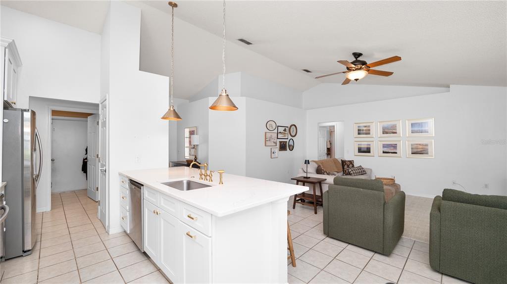 A kitchen island with a sink sits in front of an open-concept living room — 3045 LILLIAN PASS, LAKELAND, FL