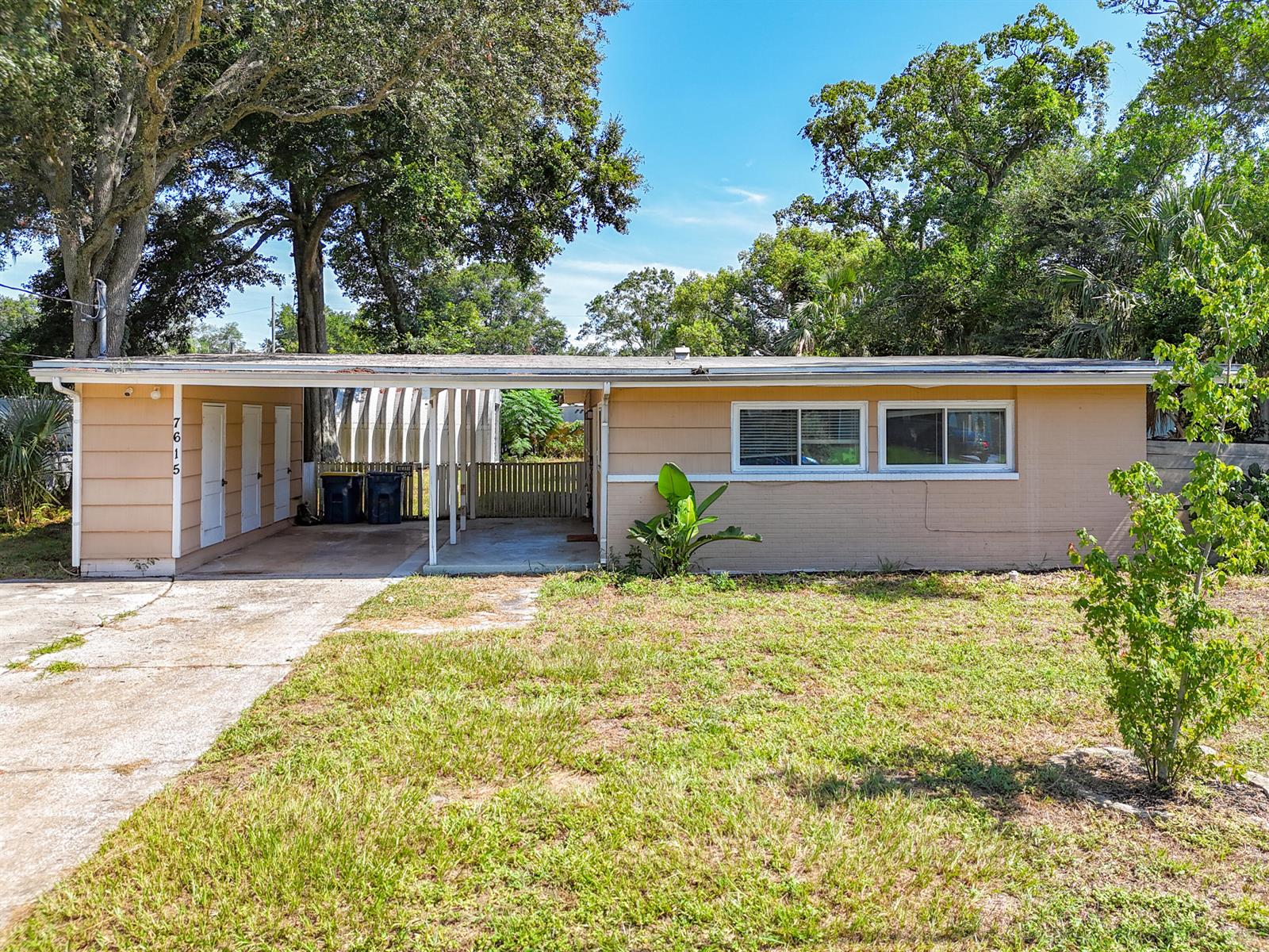 A single-story house with a carport, tan siding, and a front lawn under large trees — 7615 Mayapple Road, Jacksonville FL 32211, JACKSONVILLE, FL