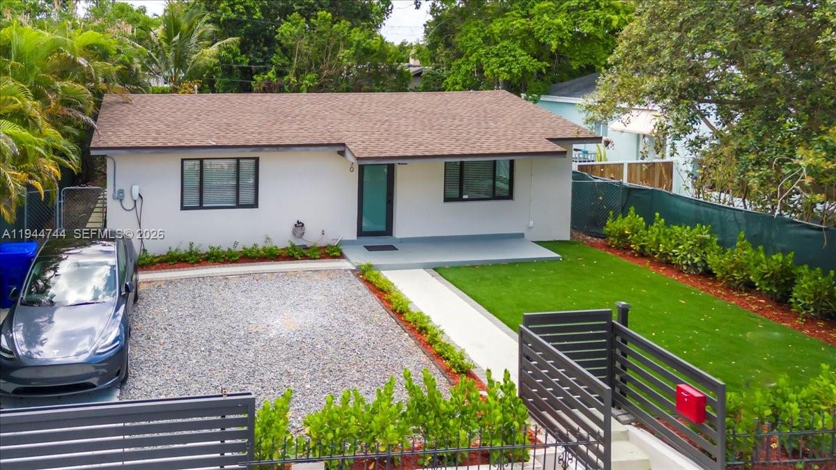 A single-story house with a gravel driveway, a green lawn, and a modern front door — 70 NW 47th Ter, Miami FL 33127, MIAMI, FL