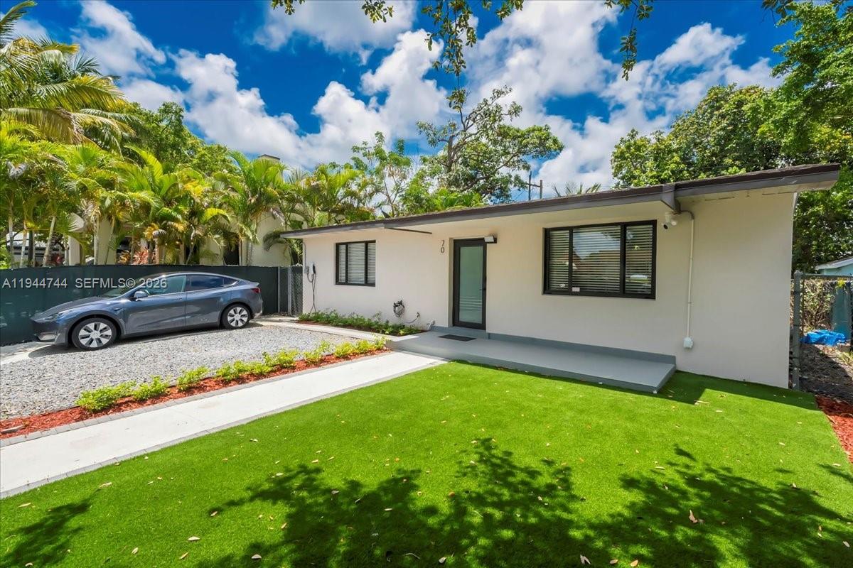 A single-story house with a gravel driveway, artificial turf lawn, and a modern front door — 70 NW 47th Ter, Miami FL 33127, MIAMI, FL