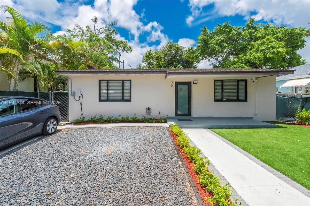 A single-story house with a gravel driveway, white exterior, and a small front lawn — 70 NW 47th Ter, Miami FL 33127, MIAMI, FL
