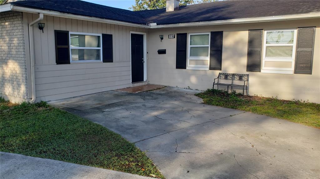 A single-story house with a concrete driveway, black shutters, and a black front door — 887 EASTBROOK BOULEVARD, WINTER PARK, FL