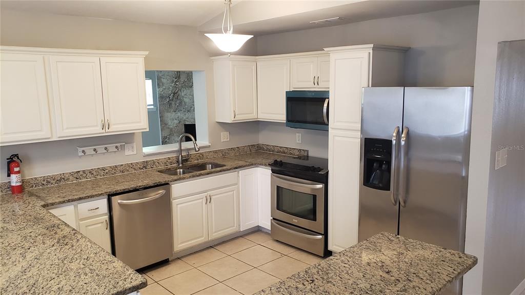 A kitchen with white cabinets, granite countertops, stainless steel appliances, and tile flooring — 887 EASTBROOK BOULEVARD, WINTER PARK, FL
