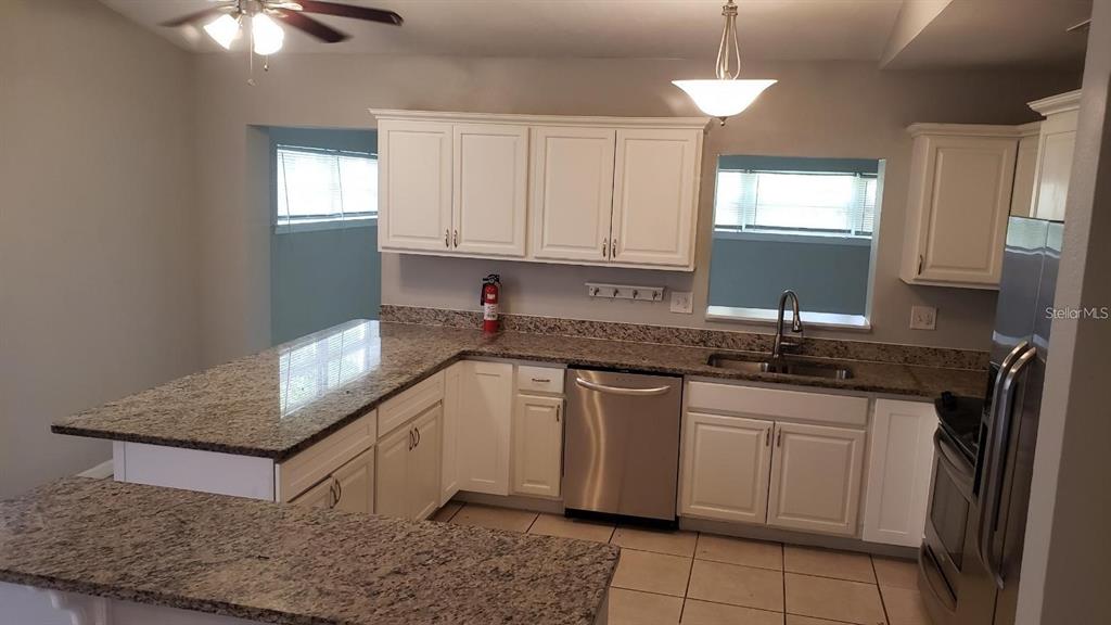 A kitchen with white cabinets, granite countertops, stainless steel appliances, and tile flooring — 887 EASTBROOK BOULEVARD, WINTER PARK, FL