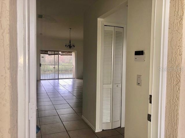 A view from a doorway looking into a tiled living area with a sliding glass door — 13336 FAIRWAY GLEN UNIT 203, ORLANDO, FL