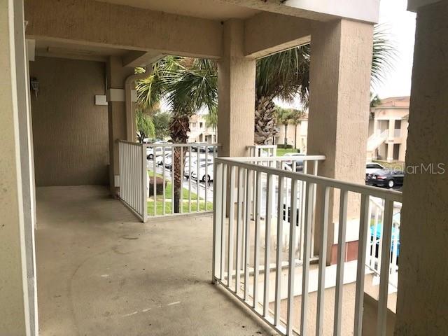 A covered balcony features a concrete floor, white railings, and views of palm trees — 13336 FAIRWAY GLEN UNIT 203, ORLANDO, FL