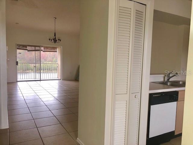 A view from a kitchen looking toward a tiled living area with a sliding glass door — 13336 FAIRWAY GLEN UNIT 203, ORLANDO, FL