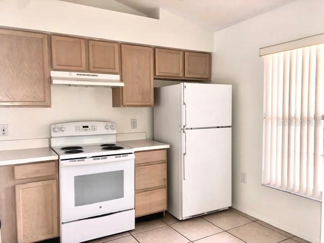 A kitchen features light wood cabinets, a white stove, a white refrigerator, and tiled floors — 13336 FAIRWAY GLEN UNIT 203, ORLANDO, FL
